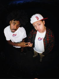 two men posing for a picture in front of a dark background