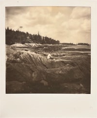 a black and white photo of a person sitting on rocks