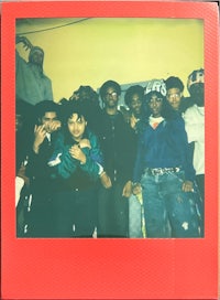 a group of people posing in front of a red polaroid