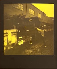 a yellow polaroid of a man standing next to a truck