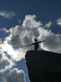 a silhouette of a person standing on top of a rock