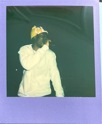 a man is holding a microphone in front of a blue polaroid