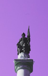 a statue of a man on a pedestal against a purple sky